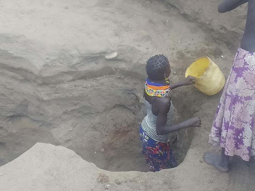 Water access in the valley — a resident draws from a hand-dug point